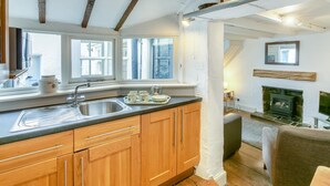 A kitchen with wooden cabinets, a stainless steel sink, and a window overlooking a street. - 2 Bed in St Ives (oc-cotsp) (Saint Ives)
