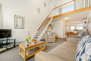 A modern living room with a staircase, a television, a coffee table with magazines, and a sofa. - 1 Bed in St Ives (oc-bpp21) (Saint Ives)
