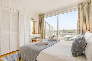 Ett hotellrum med en stor säng, ett skrivbord, en stol och utsikt över stadsbilden.