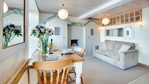 A dining area with a wooden table set for two, a sofa, and a fireplace. - 1 Bed in St Ives (oc-crab01) (St Ives)