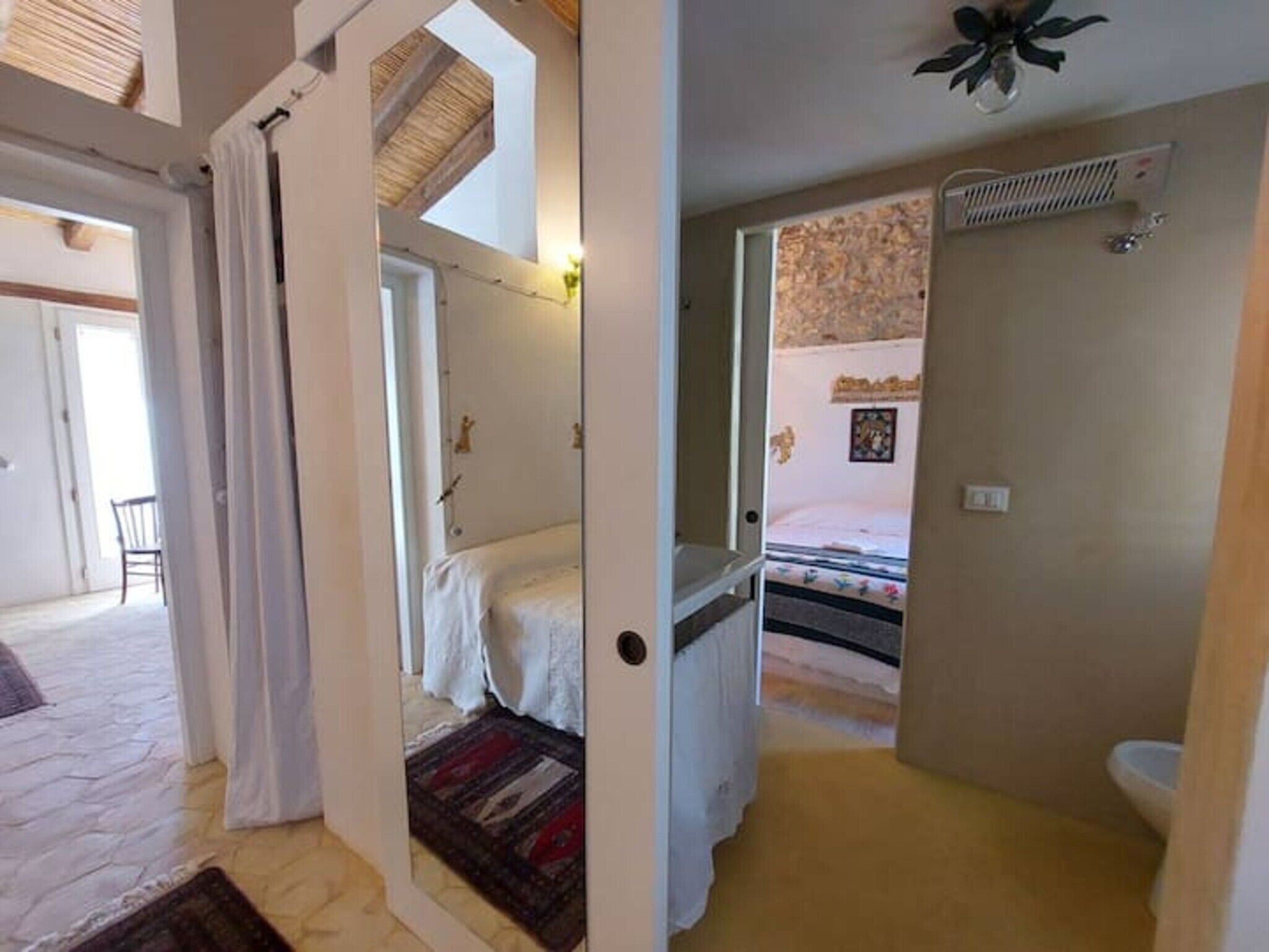 A bedroom with a bed, a bathroom with a toilet, and a hallway leading to another room.