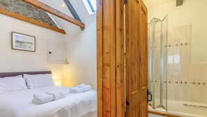 Une chambre à coucher avec un lit, une porte en bois et un espace douche.