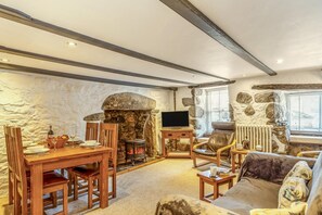 A stone fireplace, wooden furniture, and a television in a cozy living area. - 2 Bed in St Ives (oc-slipct) (St Ives)