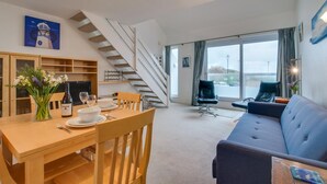En moderne stue med spiseplads, trappe og store vinduer med byudsigt.