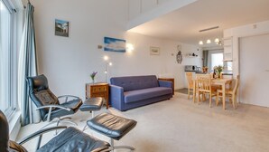 En stue med sofa, stole og et spiseområde med bord og stole.