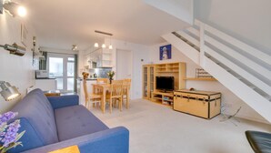 En moderne lejlighed med stue, spiseområde, køkken og en trappe.