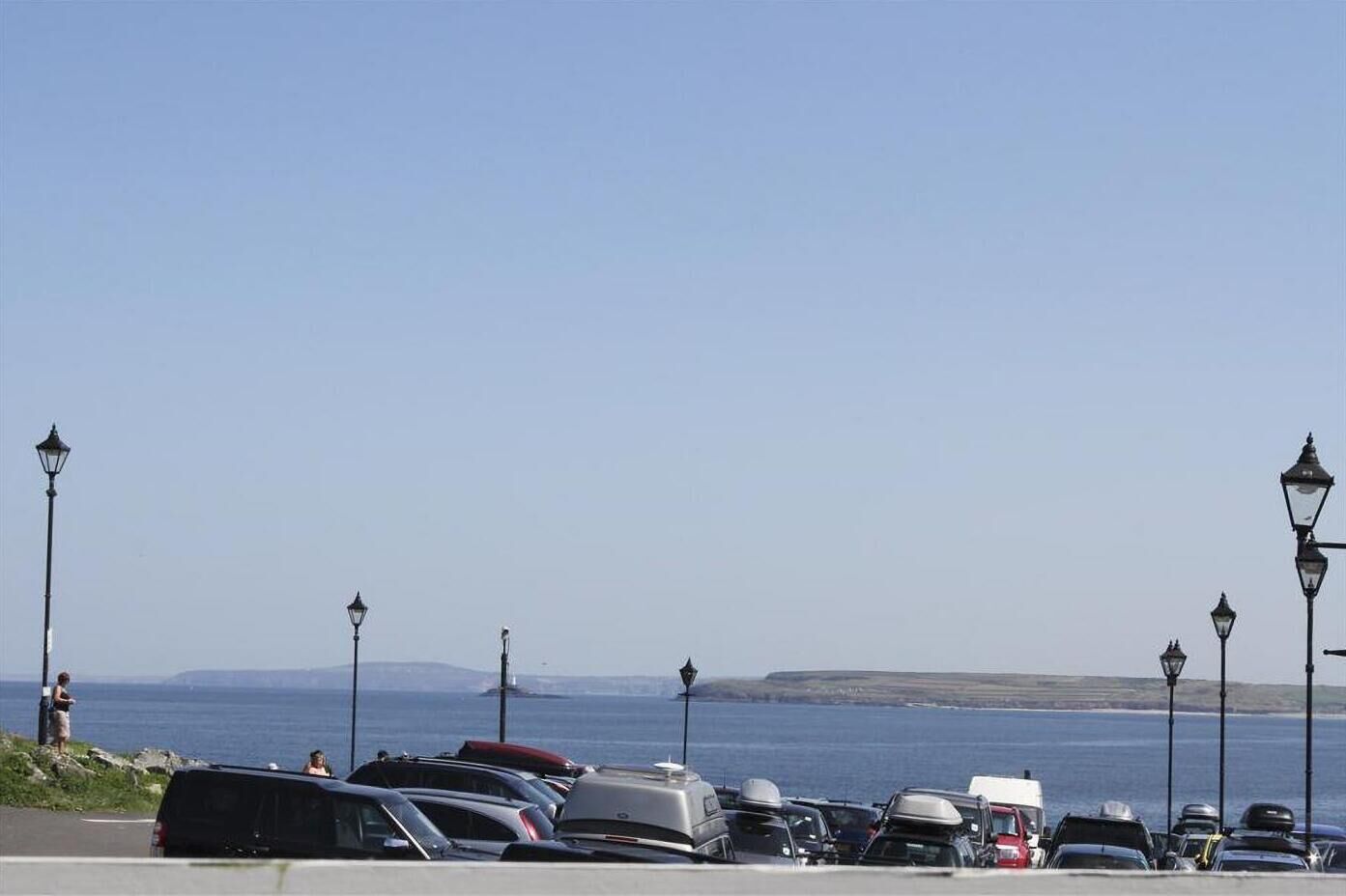 A parking lot with cars and a view of the sea.