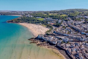 An aerial view of a coastal town with a beach, residential buildings, and a hilly landscape. - 2 Bed in St Ives (oc-redc4) (Saint Ives)