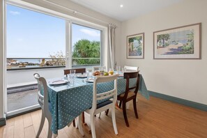 A dining area with a table set for two, a view of the sea through large windows, and two framed landscape paintings on the wall. - 3 Bed in St. Ives (oc-tregar) (St Ives)