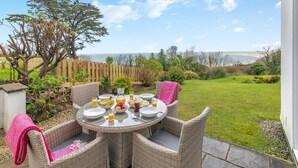 A round table with wicker chairs, a glass top, and a view of the sea. - 2 Bed in St Ives (oc-godct7) (Carbis Bay)