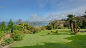 A coastal property with a grassy lawn, palm trees, and a view of the sea. - 2 Bed in St Ives (oc-godct7) (Carbis Bay)