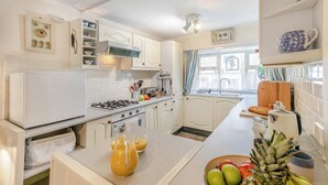 A kitchen with white cabinets, a stove, a sink, and a window with curtains. - 2 Bed in St Ives (oc-killa) (St Ives)