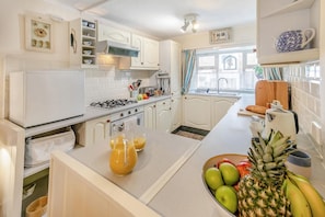 A kitchen with white cabinets, a stove, a sink, and a window with curtains. - 2 Bed in St Ives (oc-killa) (St Ives)