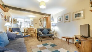 A living room with a sofa, armchairs, a coffee table, a TV, and a dining area with chairs and a table. - 2 Bed in St Ives (oc-killa) (St Ives)