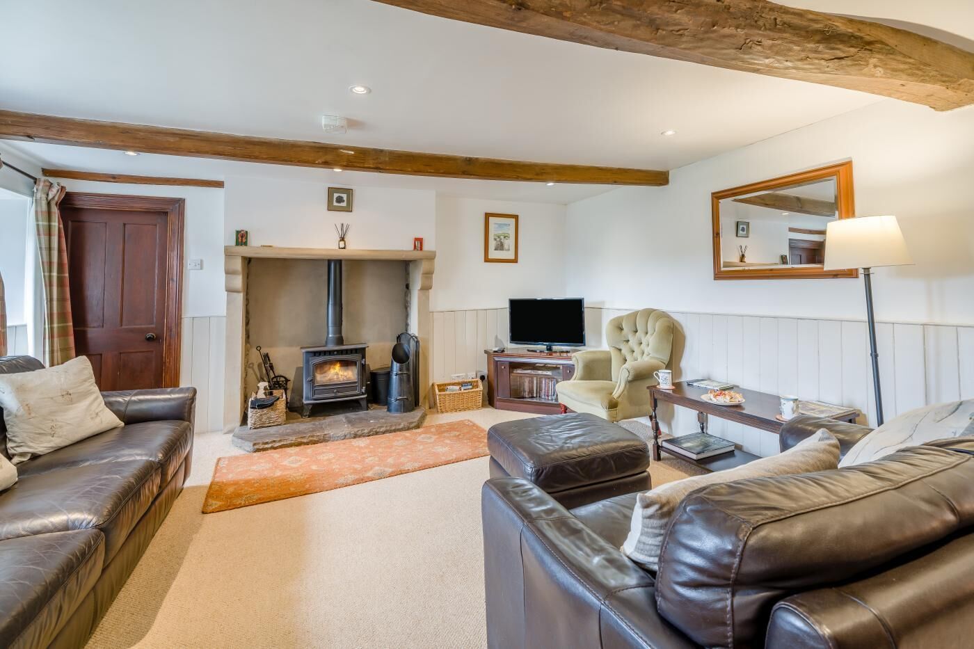 A cozy living room with a fireplace, leather sofas, a television, and a dining area.