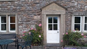 A stone building with a white door, two windows, and a bench in front. - 3 Bed in Horton-in-Ribblesdale (oc-ds933) (Horton in Ribblesdale)