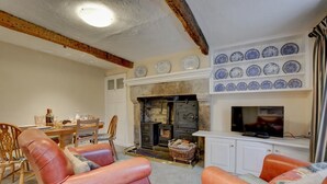 A living room with a fireplace, a television, and a dining area with a table and chairs. - 3 Bed in Horton-in-Ribblesdale (oc-ds933) (Horton in Ribblesdale)