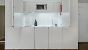 A compact kitchen with white cabinets, a microwave, a coffee maker, and a sink. - Design Studio for 3 in City Center (Oporto)