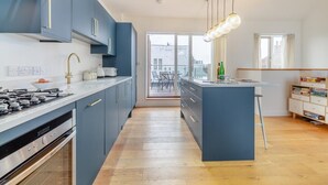 Une cuisine moderne dotée d’un îlot central, d’un coin repas avec vue et d’une bibliothèque.