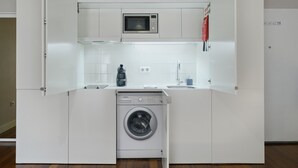 Une cuisine compacte équipée d’un lave-linge, d’un four à micro-ondes et d’un évier intégrés.
