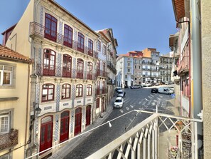 A street view with buildings featuring ornate facades and balconies, a cobblestone street, and parked cars. - Stylish Studio with balcony for 3 in Taipas Center (Oporto)