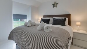 Quarto moderno com cama grande, roupa de cama listrada e decoração de estrela na parede.