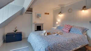 A bedroom with a bed, a dresser, a fireplace, and a staircase. - 3 Bed in Robin Hoods Bay (oc-r041) (Robin Hood's Bay)