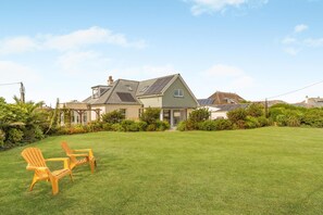A house with a large lawn and two wooden chairs. - 4 Bed in Newquay (oc-p00709) (Newquay)