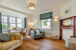 A spacious living room with a dining area, large windows, and a fireplace. - 4 Bed in Newquay (oc-p00709) (Newquay)