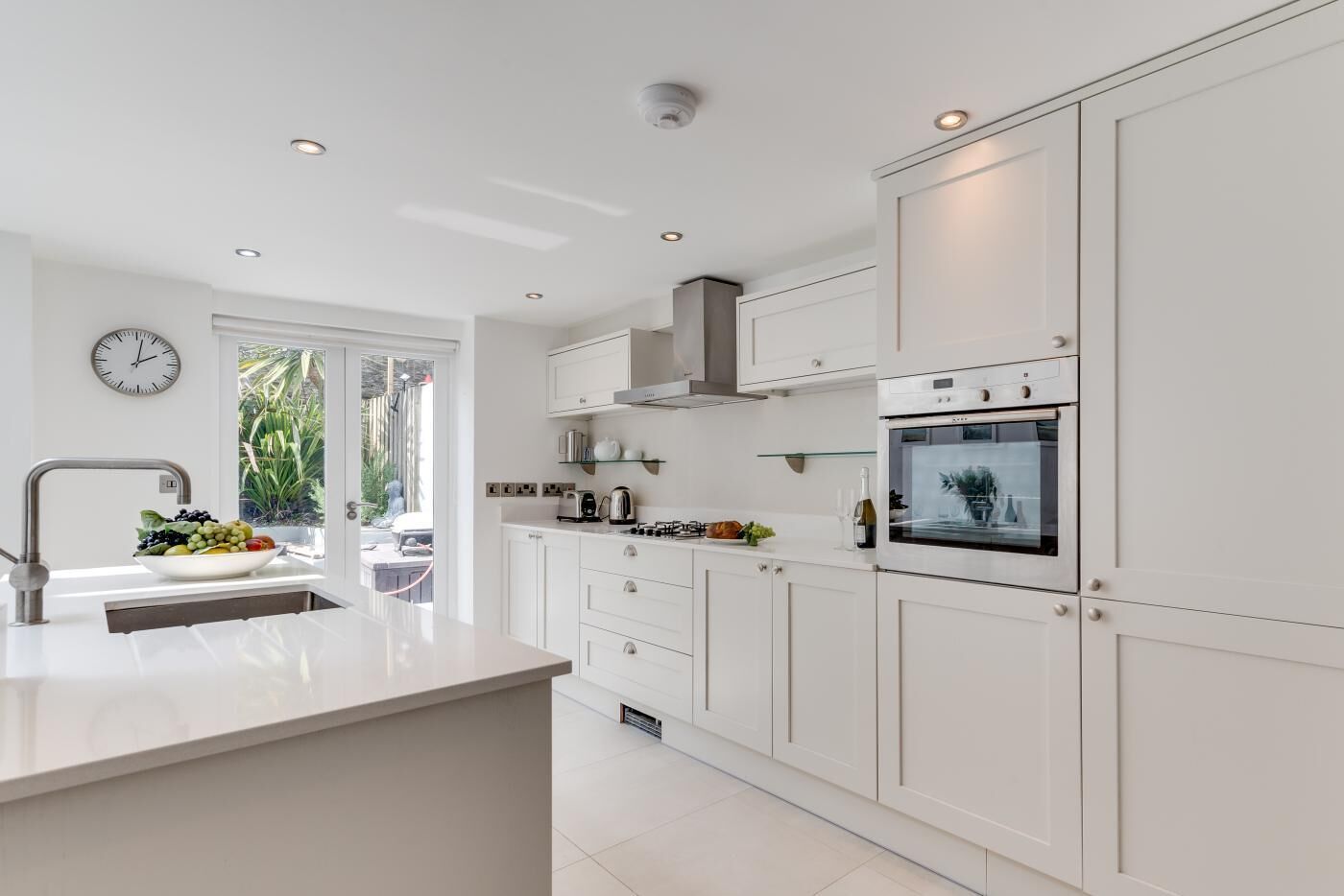 Una cocina moderna con armarios blancos, horno integrado y un amplio ventanal que proporciona luz natural.