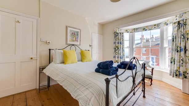 Een slaapkamer met een bed, een raam met gordijnen en een deur.