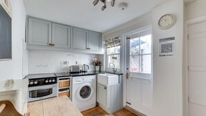 Een kleine keuken met een wasmachine, een broodrooster en een spoelbak.