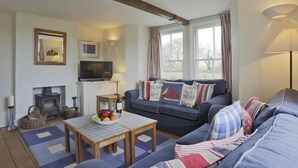 A cozy living room with a sofa, a table with fruit, a television, and a fireplace. - 3 Bed in Walberswick (oc-aaferr) (Walberswick)