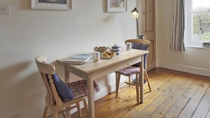 A cozy room with a wooden table, two chairs, a lamp, and artwork on the walls. - 3 Bed in Walberswick (oc-aaferr) (Walberswick)