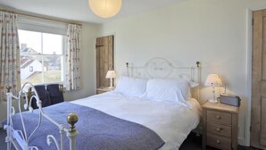 A bedroom with a bed, bedside tables, a lamp, and a window with curtains. - 3 Bed in Walberswick (oc-aaferr) (Walberswick)