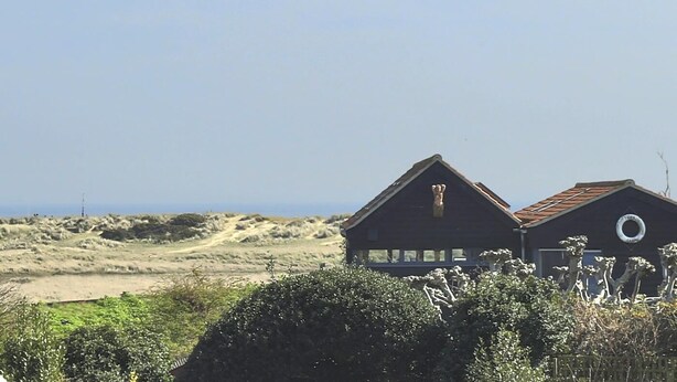 Two buildings with a sandy landscape and a clear sky in the background. - 3 Bed in Walberswick (oc-aaferr) (Walberswick)