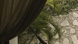 Ein Zimmer mit einem Bett, einer Steinwand und Blick auf einen Pool.