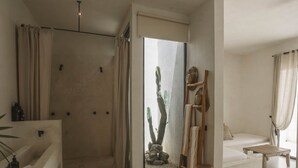 Ein modernes Badezimmer mit Dusche, Badewanne und einem großen Fenster mit Blick auf Kakteen und Felsen.