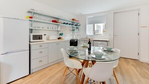 Una cucina moderna con mobili bianchi, un tavolo da pranzo in vetro e sedie bianche.