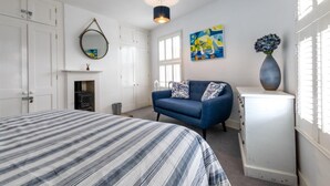 Ein Schlafzimmer mit einem Bett, einem blauen Sofa, einem Schminktisch und einem Bild.