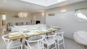 A modern dining area with a high ceiling, white furniture, and a table set for four.