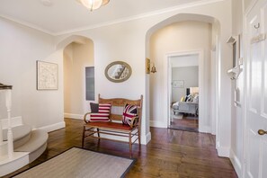 Un couloir avec un banc en bois, un miroir et un escalier.