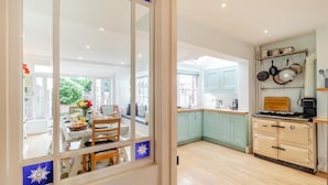 Une cuisine avec des meubles de couleur bleu clair, une cuisinière et un coin repas comprenant une table et des chaises.