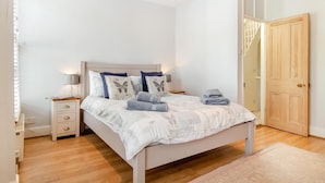 Une chambre à coucher avec un lit, des tables de chevet, une porte et une fenêtre.