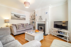 Ein Wohnzimmer mit Sofa, Couchtisch, Fernseher, Kamin und Bücherregalen.