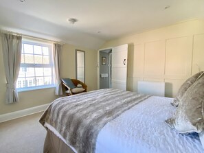 Ein Schlafzimmer mit Bett, Stuhl, Fenster und Tür.
