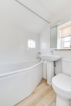 A modern bathroom with a white bathtub, sink, and toilet. - 2 Bed in Southwold (oc-aaheat) (Southwold)