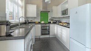 Une cuisine moderne avec des meubles blancs, un four encastré, un four à micro-ondes et un réfrigérateur.