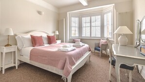 Une chambre à coucher bien rangée, avec un lit, des tables de chevet, un bureau et une chaise.