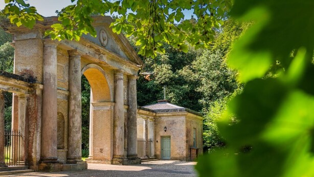 An ancient stone structure with columns and an arched entrance, surrounded by greenery. - 1 Bed in Wells-next-the-Sea (oc-1939) (Wells-next-the-Sea)